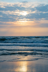 Beautiful sunset on the Baltic Sea with waves and reflections on the water, vertical