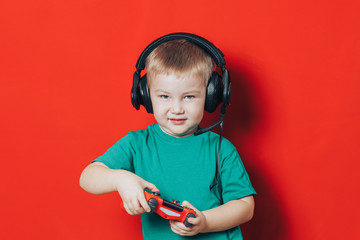 small boy in headphones and joystick on red background