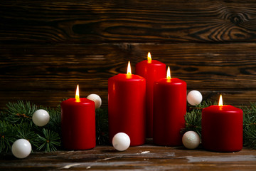 Bunch of red candles burning on wooden table with traditional christmas pine decoration on wood textured background with a lot of copy space for text.