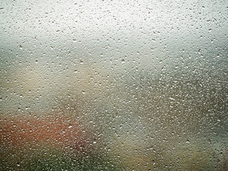 Fototapeta na wymiar Rain drops on the glass in the spring afternoon. Close up of a window with rain drops falling down.The rain drops on household windows. Focus on rain drops. concept of sadness, frustration