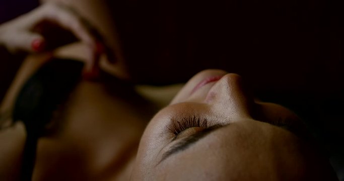 sensual woman dressed in black sexy lingerie is stroking her breast lying in bedroom