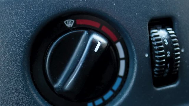 Closeup of hand adjusting the air conditioner button in the car. Man using automobile air conditioning system. Dual climate control in the car.
