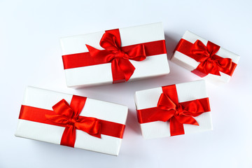 Bunch of christmas presents wrapped in red and white paper tied with shiny silk bow. Multiple new years gifts in red and white wrapping. Top view, close up, copy space, background, flat lay.