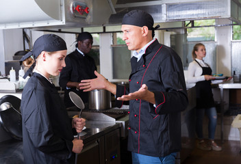 Angry chef talking to female assistant