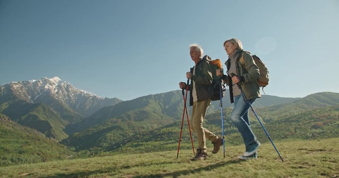 Mature caucasian couple on vacation, having a hike in spring mountains, spending time together after retirement together travelling - tourism, pension concept 4k