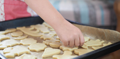 a child at home cuts out cookie cutters.