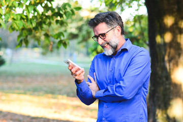 Senior man websurfing on tablet outside the house. Senior mature man walking using tablet pc. Senior man uses his digital tablet. Older man using tablet computer in park