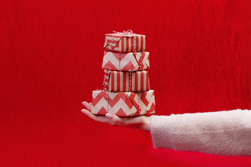 Woman holding Christmas presents on a Red table background...