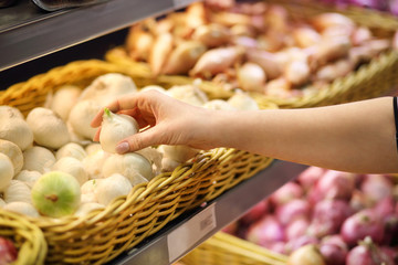 Female hand choosing onion in the store. Concept of healthy food, bio, vegetarian, diet.
