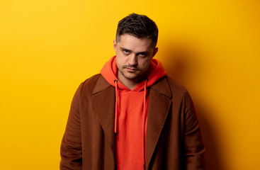 Angry man in coat on yellow background