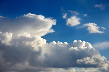 Naklejka premium Blue sky with a big white clouds in the light of the sun. Large fluffy cumulonimbus clouds at sunny day. Meteorology, weather forecast