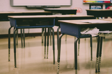 Contemporary student desks placed into rows within brightly lit room filled with studying materials