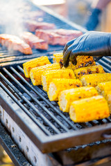 BBQ corn on an open grilles fire.Hand in glove overtakes pumpkin corn