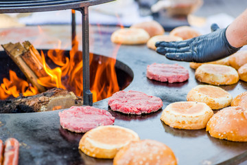 cook hands in gloves grill burger beef patties on the grill. Open fire on the barbecue