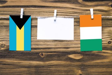 Hanging flags of Bahamas and Cote D'Ivoire attached to rope with clothes pins with copy space on...