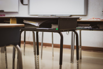 Contemporary student desks placed into rows within brightly lit room filled with studying materials