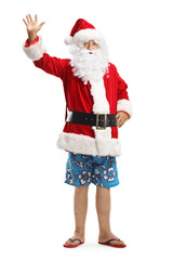 Santa Claus in summer shorts and flip-flops waving at the camera