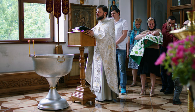 The sacrament of baptism. Christening the baby. Child, priest and parishioners.