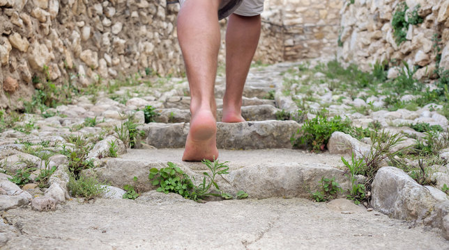 Male bare feet climb old stone steps