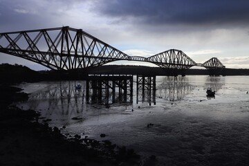 Fototapeta na wymiar Firth of Forth at low tide with rail bridge casting reflection in water