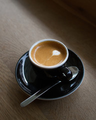 Espresso machiato with heart shaped latte art on a wooden counter