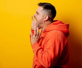 Handsome man in hoodie on yellow background