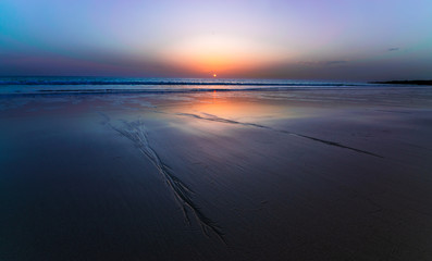 Amanecer en la playa con el sol saliendo en el horizonte