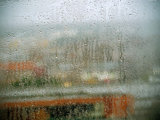 Rain drops on the glass in the spring afternoon. Close up of a window with rain drops falling down.The rain drops on household windows. Focus on rain drops. concept of sadness, frustration