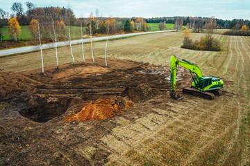The modern excavator performs excavation work on the farm field