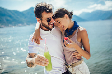 Fototapeta na wymiar Young couple eating fruit on the beach- summer party with friends and healthy food concept