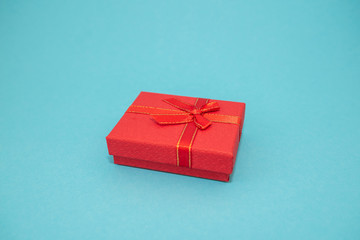 Red Gift box with red ribbon on blue background. Top view with copy space.