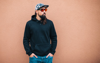 City portrait of handsome hipster man with beard wearing black blank hoodie or hoody with space for your logo or design. Mockup for print