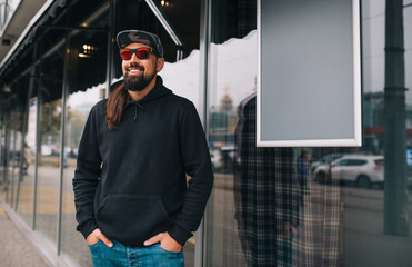 City portrait of handsome hipster man with beard wearing black blank hoodie or hoody with space for...