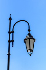 Fototapeta na wymiar Old lantern on a metal post against blue sky