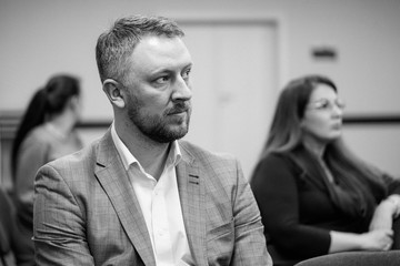 Portrait of young successful businessman in the office. Handsome man at the seminar. Blurred background. Seriuos and confident man.