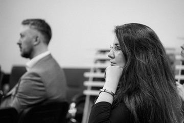 Focused young beautiful long haired woman at seminar. Seminar Audience in Training Room. Watch Presentation. Rear View of Audience People Listening to Speaker.