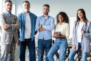 Fototapeta premium Portrait of creative business team standing together and laughing. Multiracial business people together at startup