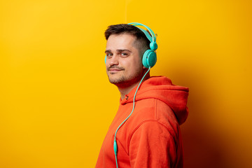 Funny man with headphones on yellow background