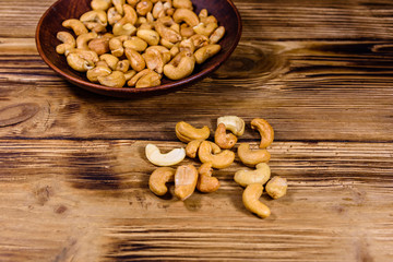 Ceramic plate with roasted cashew nuts on a wooden table