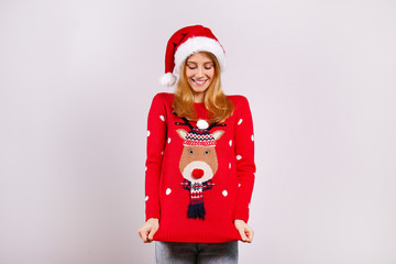 Beautiful smiling young woman wearing knitted sweater celebrating Christmas. Attractive blonde female, new years eve. Ugly Christmas sweater concept. Copy space background, close up portrait, isolated