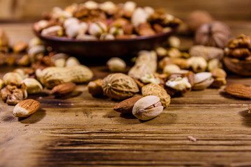 Various nuts (almond, cashew, hazelnut, pistachio, walnut) in ceramic plate on a wooden table. Vegetarian meal. Healthy eating concept