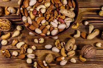 Various nuts (almond, cashew, hazelnut, pistachio, walnut) in ceramic plate on a wooden table. Vegetarian meal. Healthy eating concept. Top view