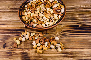 Various nuts (almond, cashew, hazelnut, pistachio, walnut) in ceramic plate on a wooden table. Vegetarian meal. Healthy eating concept