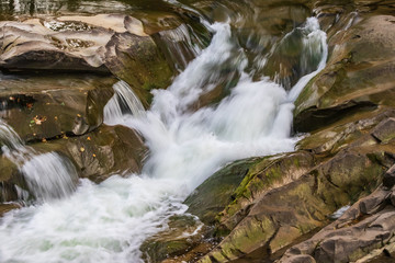 Fototapeta premium Mountain stream and rocky waterfall. Tourist and geological landmark. Powerful waterfall Probij in Yaremche. Carpathians, Ukraine.