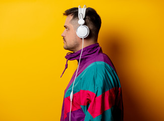 Style man in 90s tracksuit with headphones on yellow background