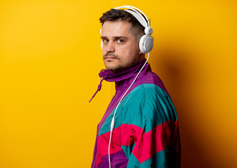 Style man in 90s tracksuit with headphones on yellow background