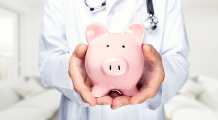 Male doctor holding piggy bank