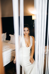 Elegant bride in a white dress sits near the dressing table. View from the balcony