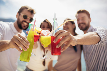 Friends at the beach drinking cocktails having fun on summer vacation