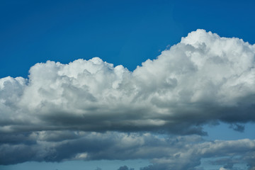 Naklejka na ściany i meble Volumetric clouds against a contrasting sky. Beautiful big clouds on a background of blue sky.